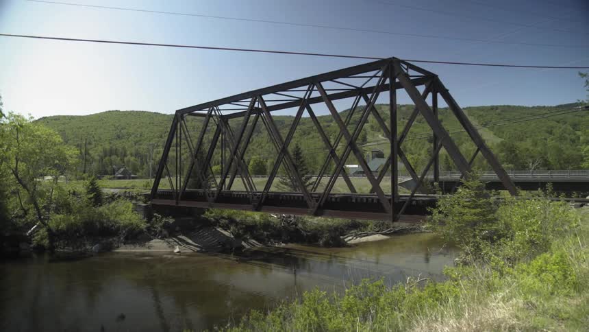 Trees blow gently near a bridge over a creek