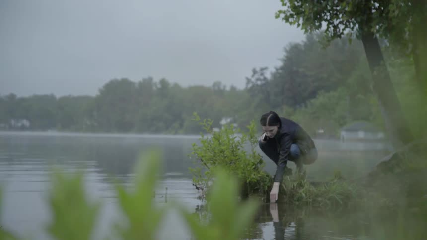 Woman dips her fingers in the lake