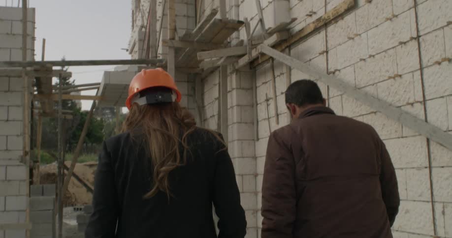 Man and woman walk by an old run down building