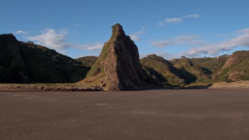 Waves roll onto the shore of a beach at the base of a cliff