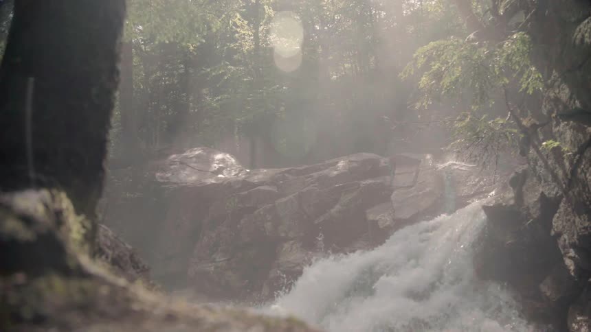 A river rushing over rocks creates mist in the air