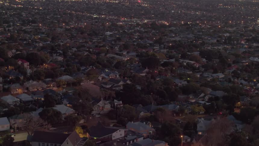 Lights gleam in houses and on streets in a community at dusk