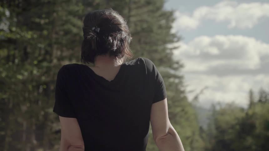 A woman leans back as she takes in a view of pine trees and mountains