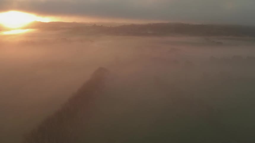 Fog blankets a landscape at dawn