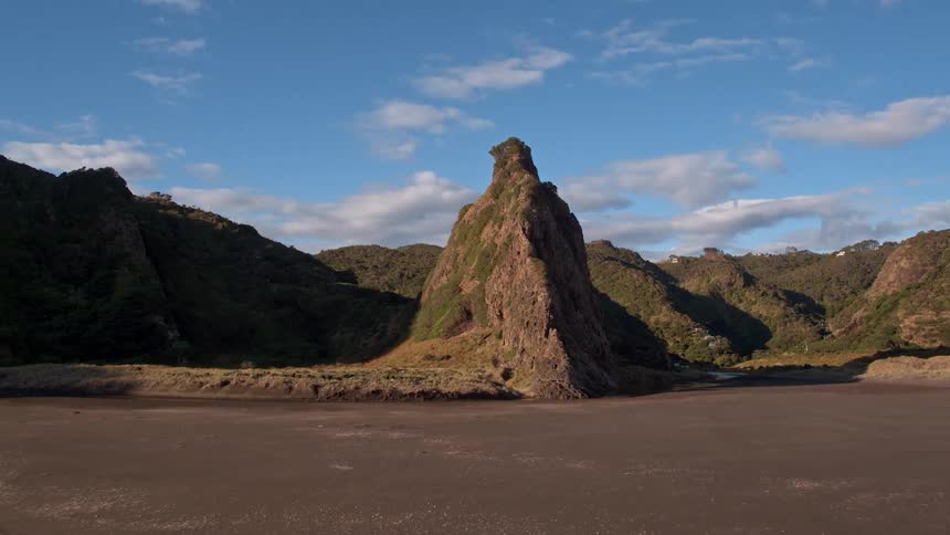 Waves roll onto the shore of a beach at the base of a cliff