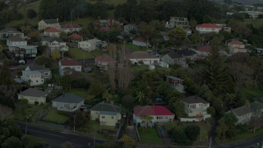 Vehicles drive through a neighborhood at dusk