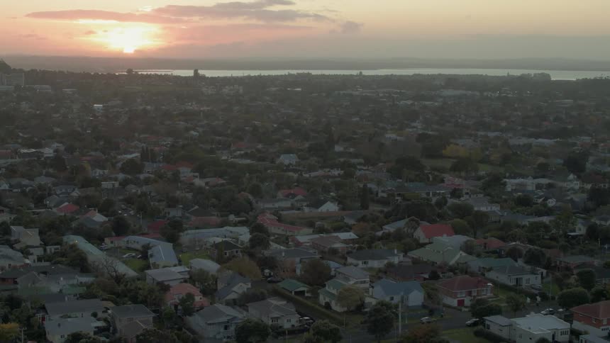 The sun sets over a coastal city and neighborhood