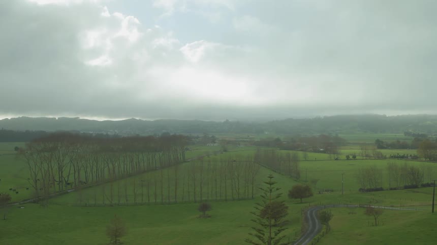 Clouds and mist roll over rural fields and hills