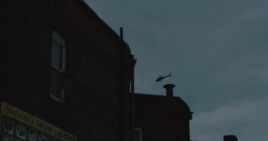 A helicopter flies over buildings at dusk