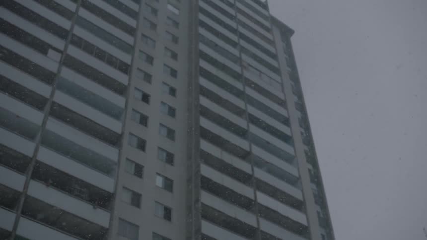Snow falls outside a high rise in the city