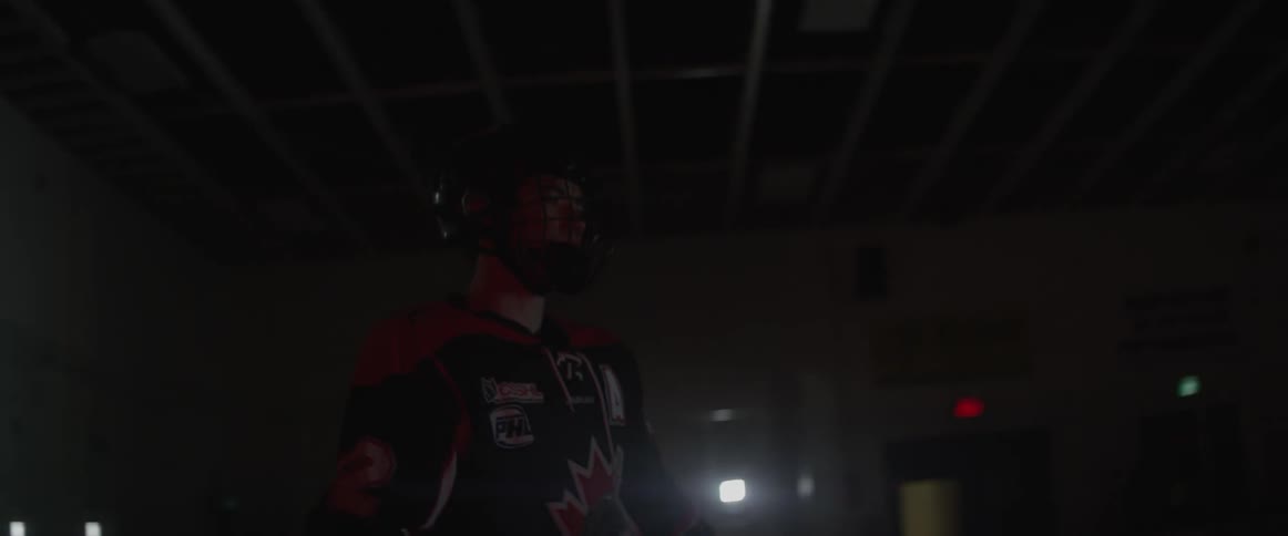 A hockey player skates around a dark rink