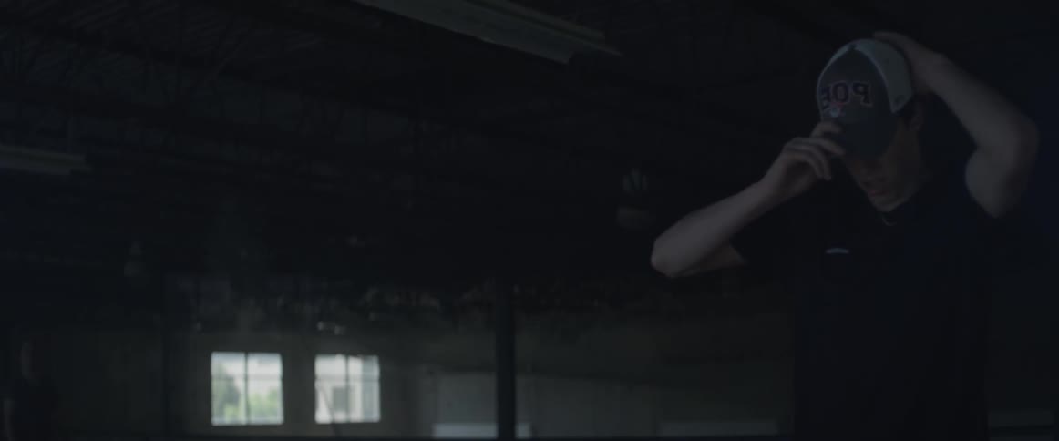 A teenage boy is putting on a baseball cap as he stands inside