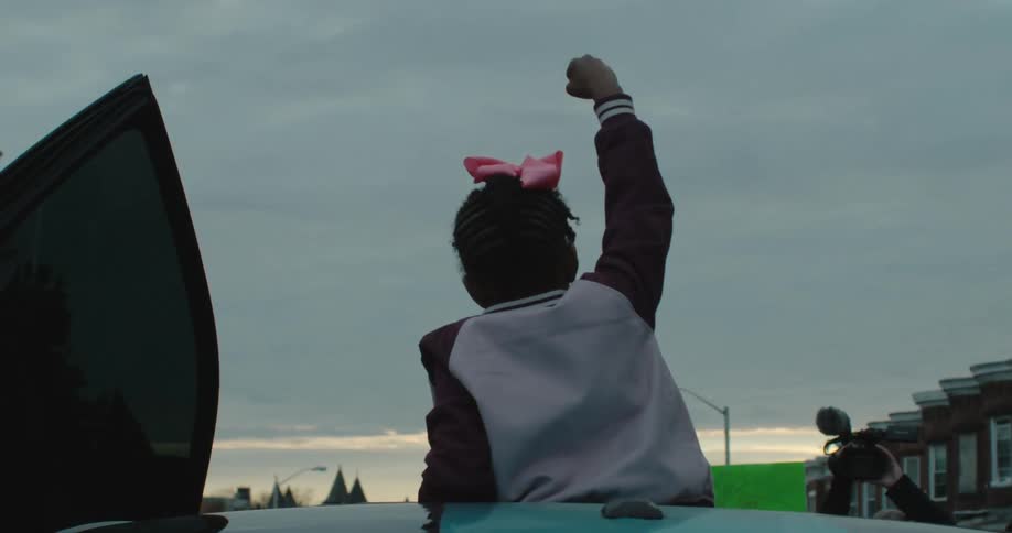A girl with a bow in her hair and fist raised into the air