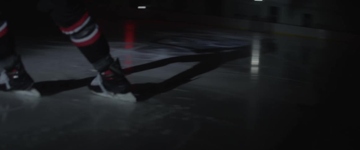 Person ice skates on an ice rink in the dark