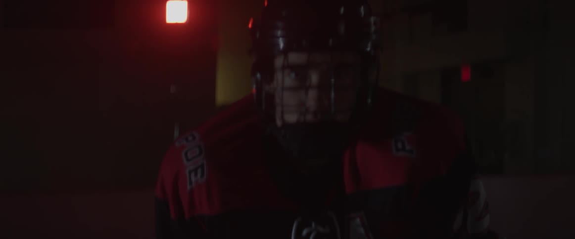A hockey player skates on the ice in the dark