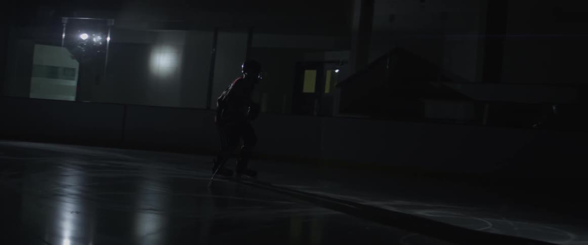A hockey player ice skates in the dark