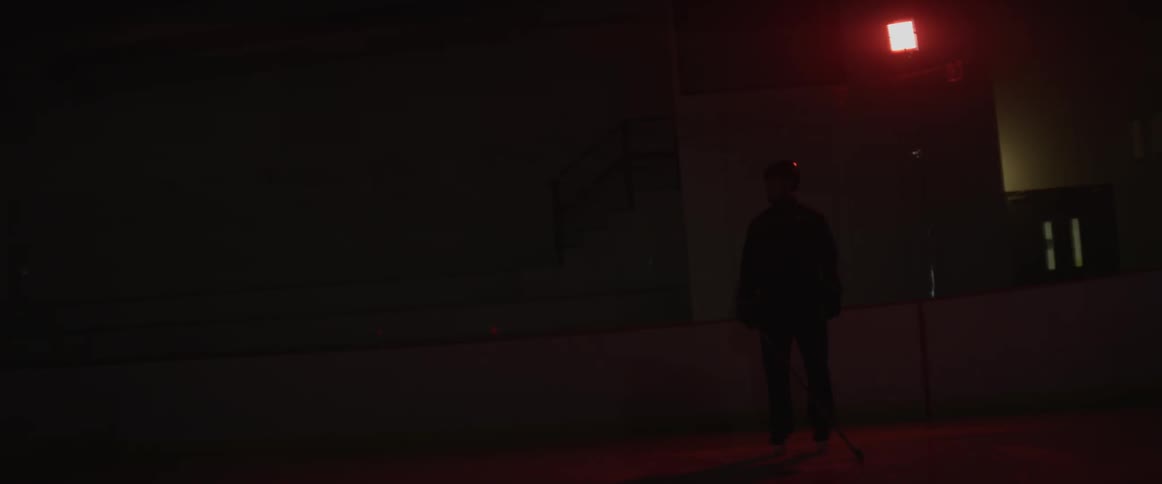 A hockey player skates on the ice in the dark