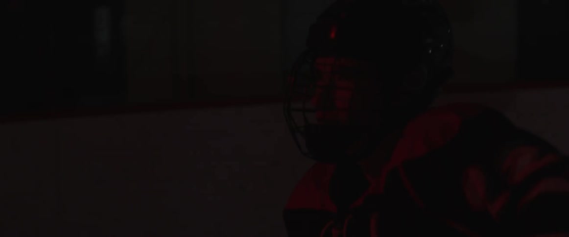 A hockey player glides on the ice in a dark arena