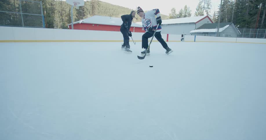 Two people play hockey outside