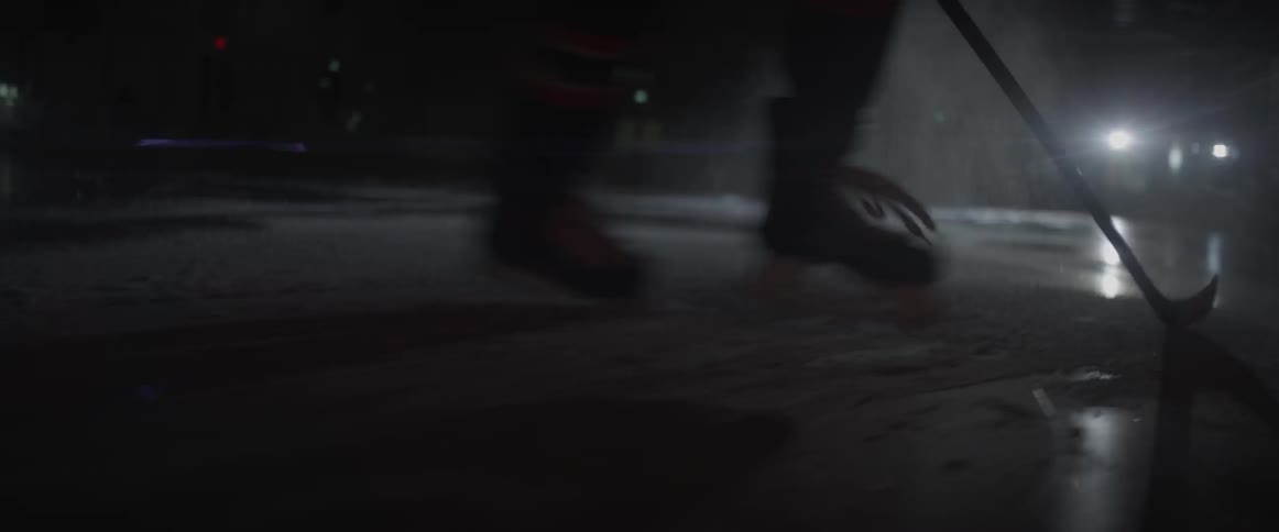A hockey player skates on rink at night outdoors