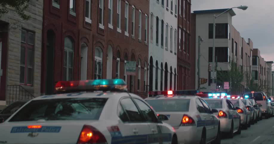Long line of parked police vehicles with lights on