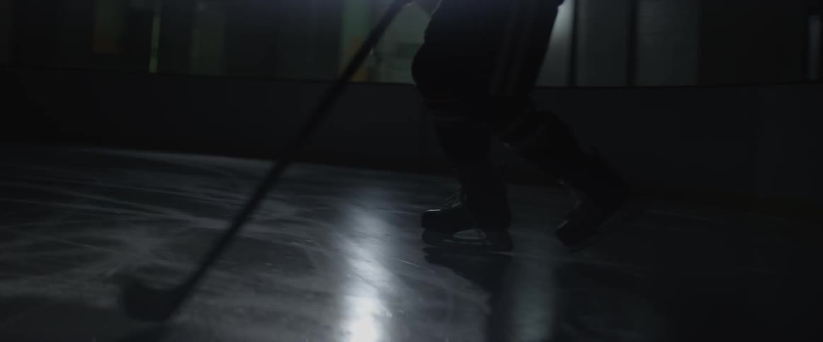 A hockey player skates on the ice in the dark