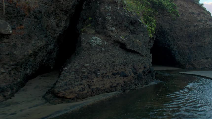 The tide flows at the base of cliffs on a beach