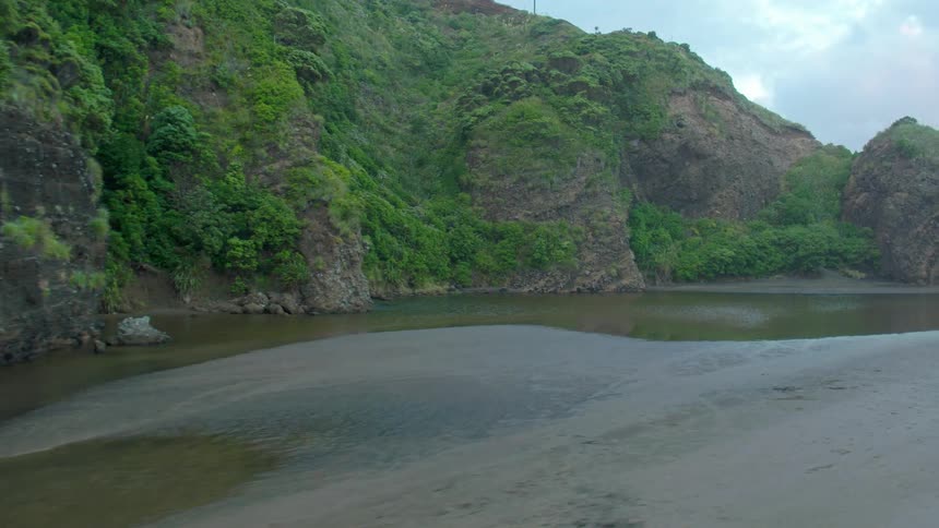 The tide flows at the base of cliffs on a beach