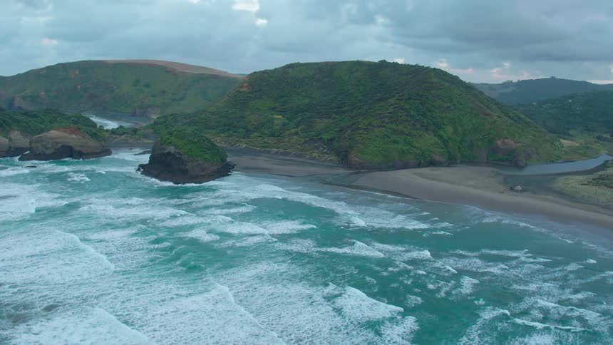 Waves roll onto a shore near hills