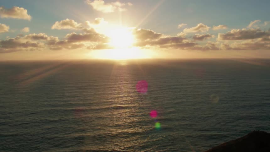 The sun is setting on the horizon on the coast