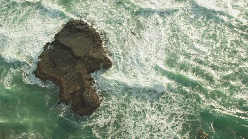Waves crash over rocks as they roll toward the beach
