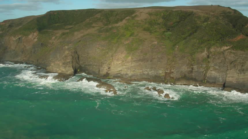 Waves crash over rocks at the base of cliffs