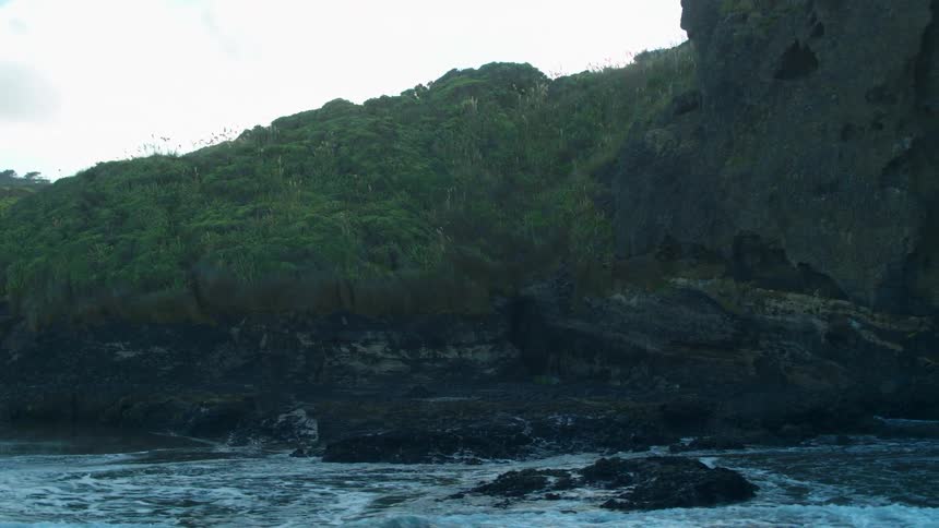The tide flows at the base of cliffs on a beach