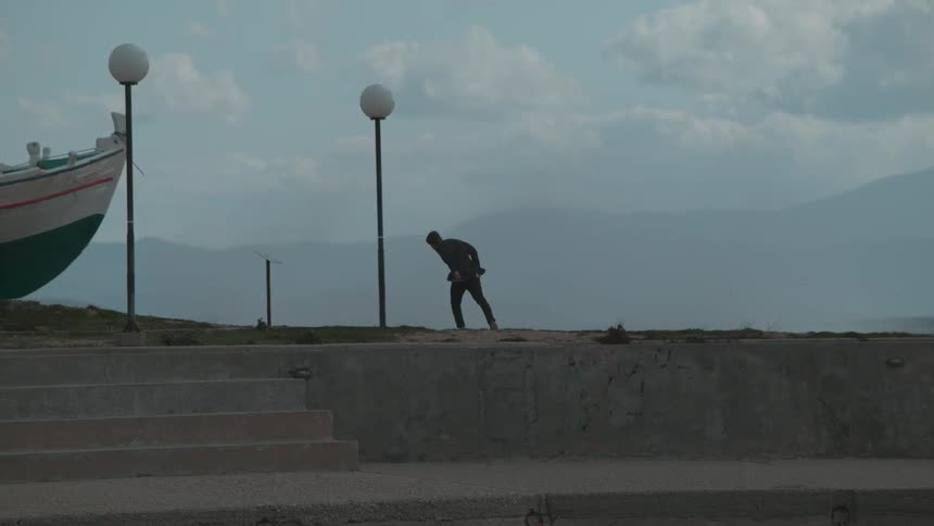 A man in slow motion on land with the prow of a boat nearby