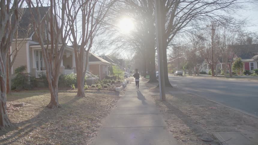 A woman is jogging in a suburban neighborhood during the day