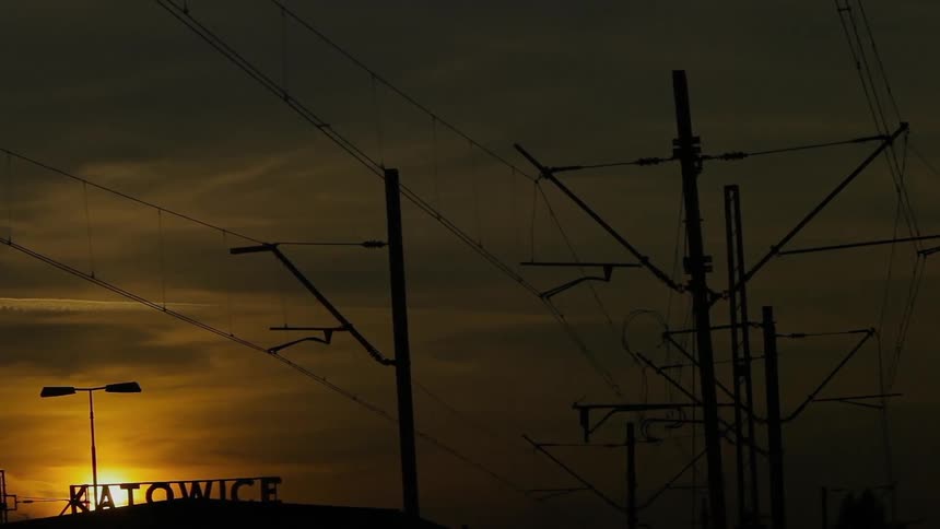 Utility poles with electrical wires with the sky and the sun in the background
