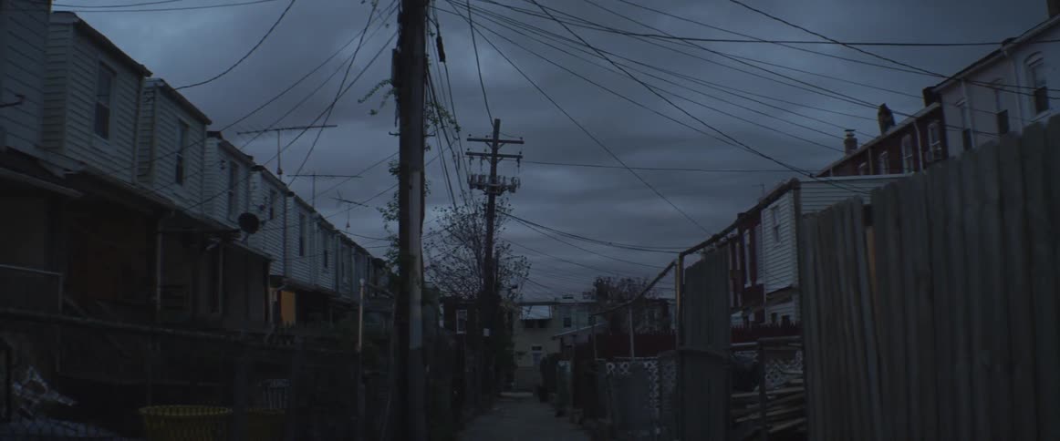 A back alley between some tenement houses with lots of telephone wires