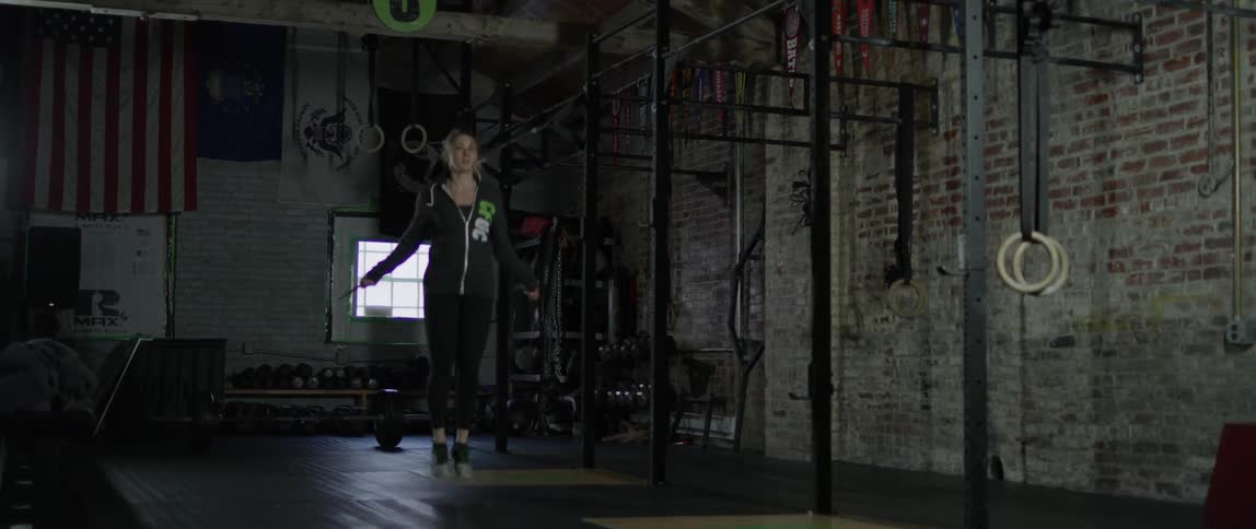 A woman jumping rope in a dark gym