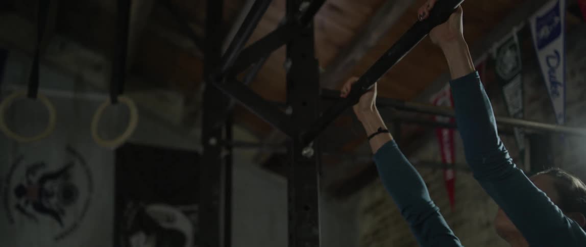 A female athlete is doing leg pull ups in a gym