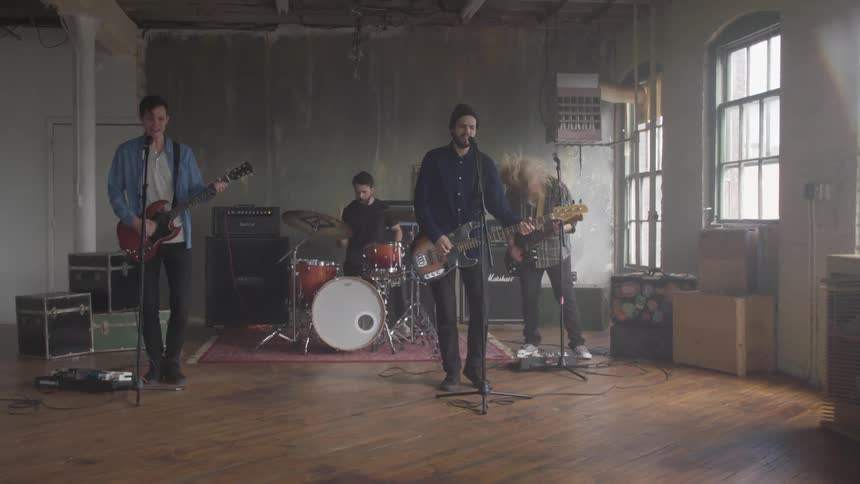 A band comprised of young men is playing music during the day