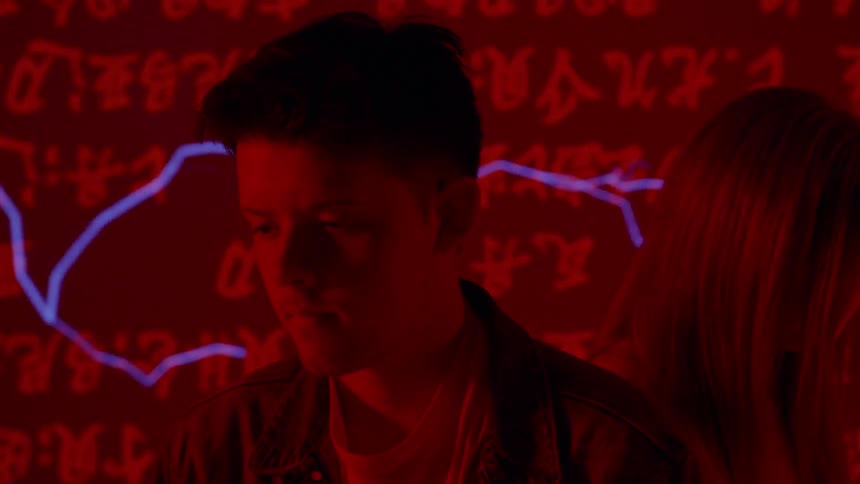 A young man and woman stands in front of a projection