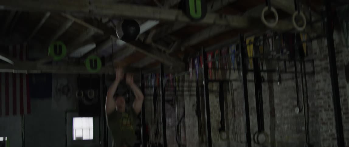 A man squats and tosses a medicine ball in the air