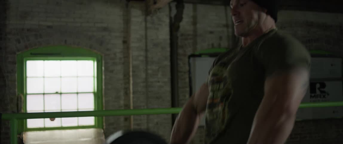 A man is deadlifting weights in a gym during the day