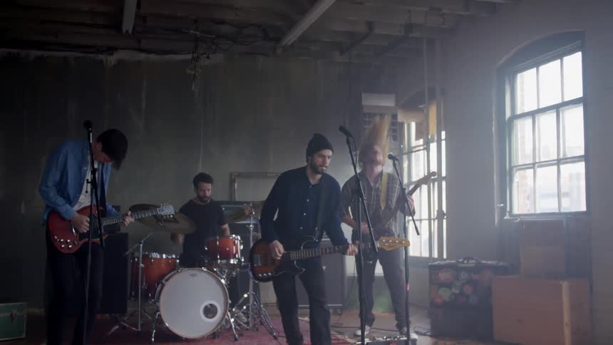 A rock band is playing in a building during the day