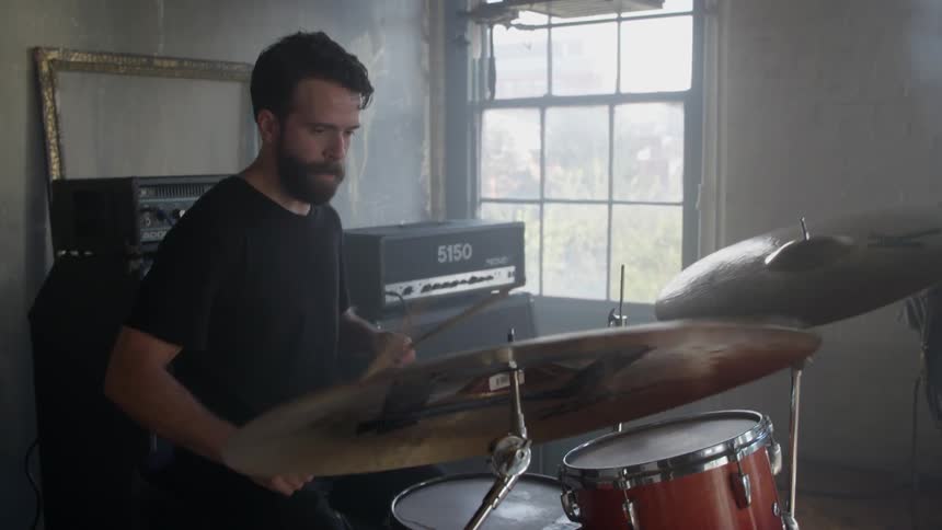 A man plays drums in a band during the day