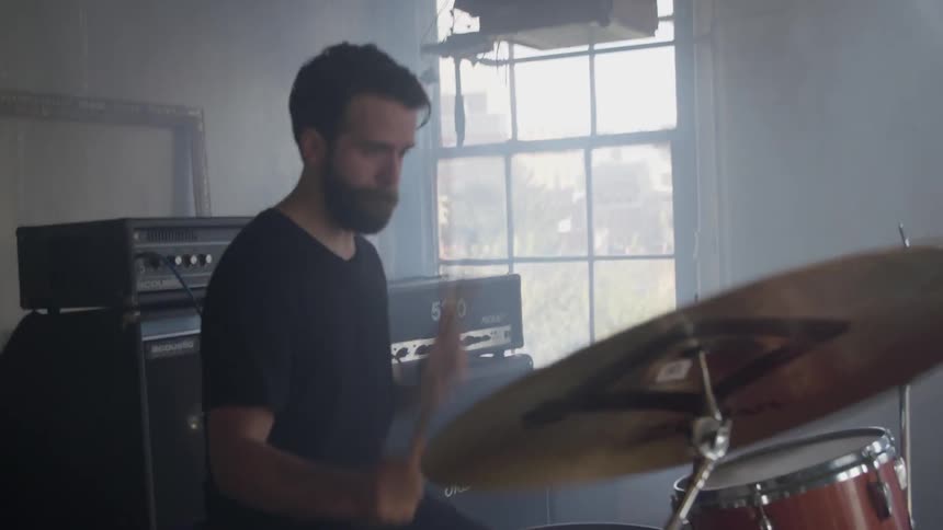 A man plays drums in a band during the day