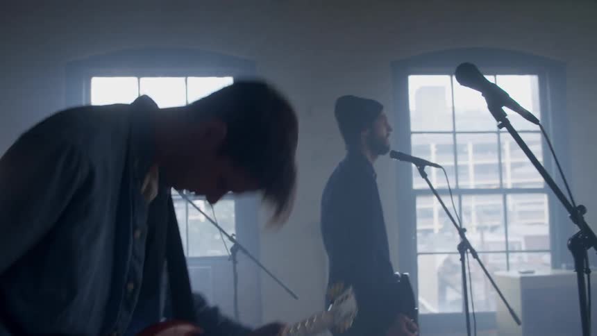 A rock band is playing music inside during the day
