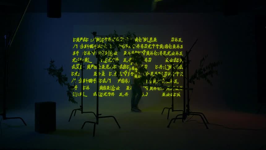 A young woman walks past a wall projecting text