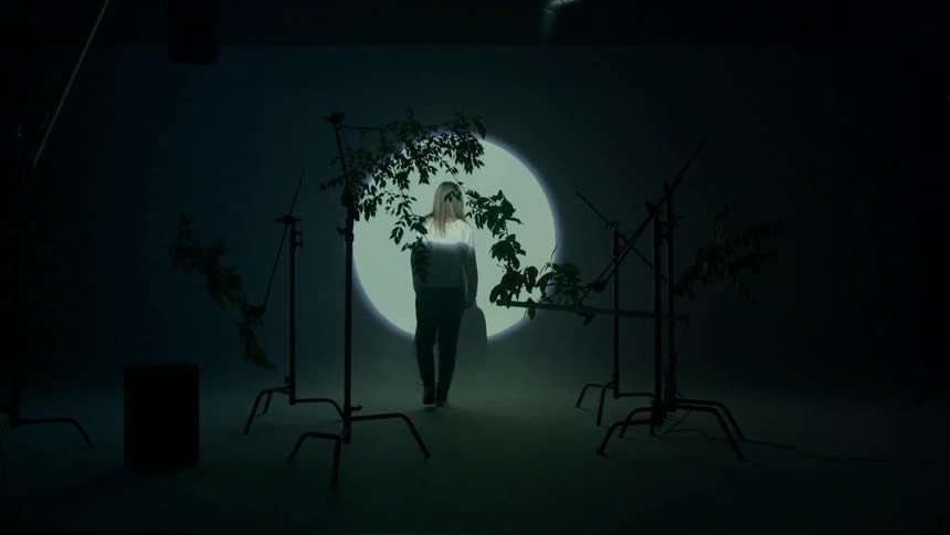 A person stands in a spotlight in a dark room