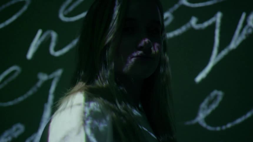 A woman stands in front of multi-colored projections
